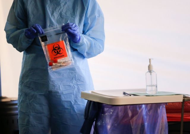 A nurse holds a completed test with patient samples at a drive-through testing site for coronavirus, flu and RSV, currently by appointment for employees at UW Medical Center Northwest