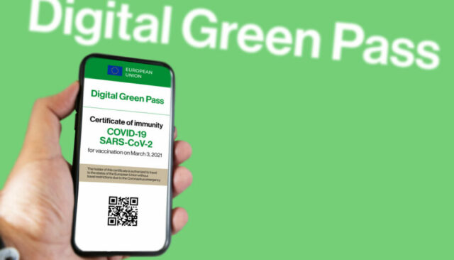 The digital green pass of the european union with the QR code on the screen of a mobile held by a hand with a blurred green background